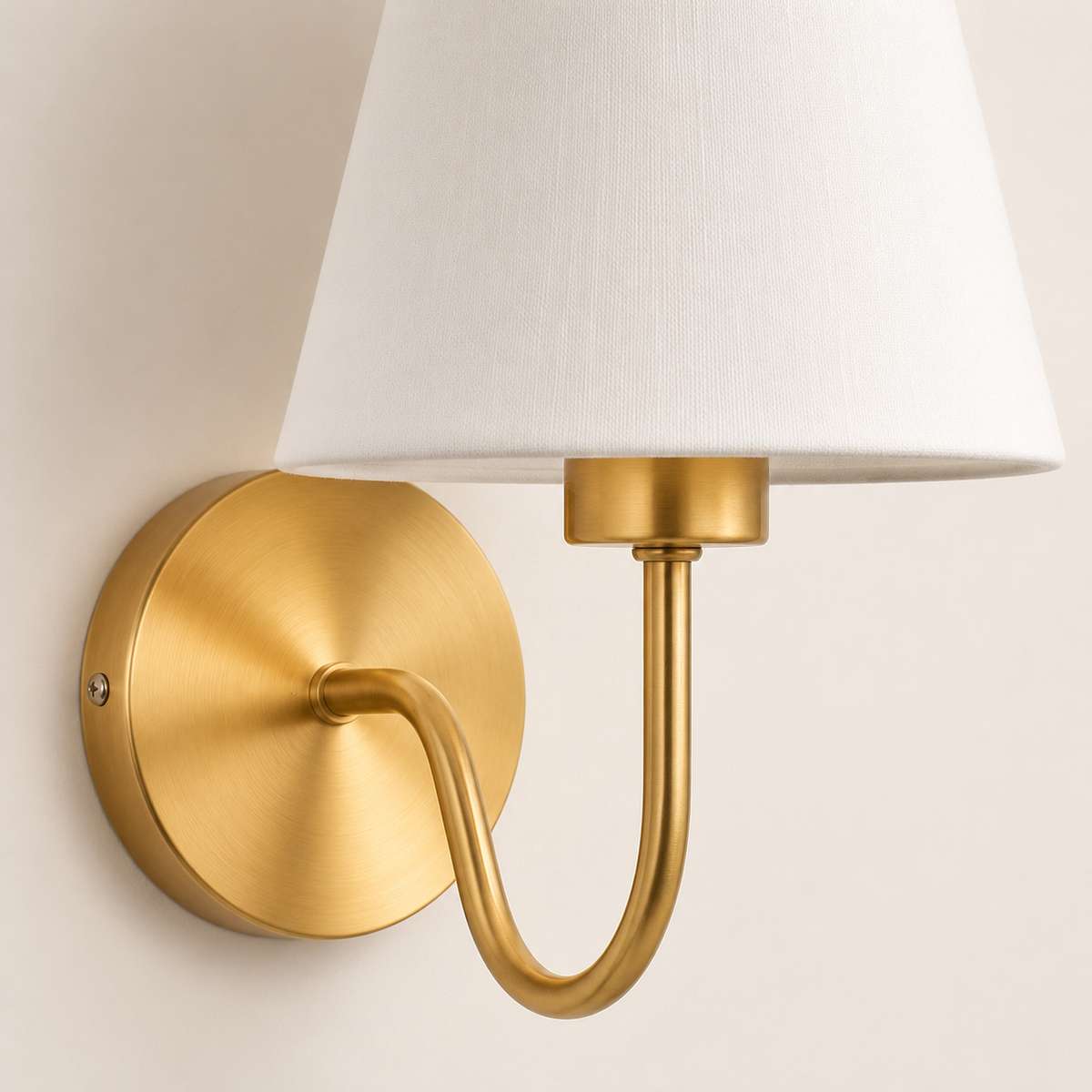 Detalhe da base circular, do braço curvo dourado e da cúpula de tecido da Arandela Elora.