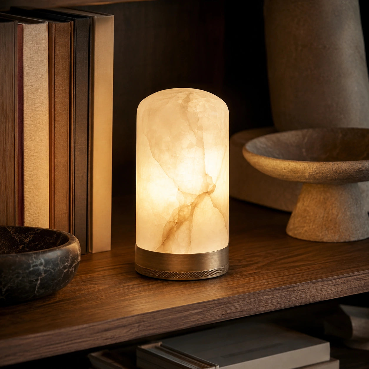 Luminária Portátil Éloise acesa sobre mesa de cabeceira em quarto elegante