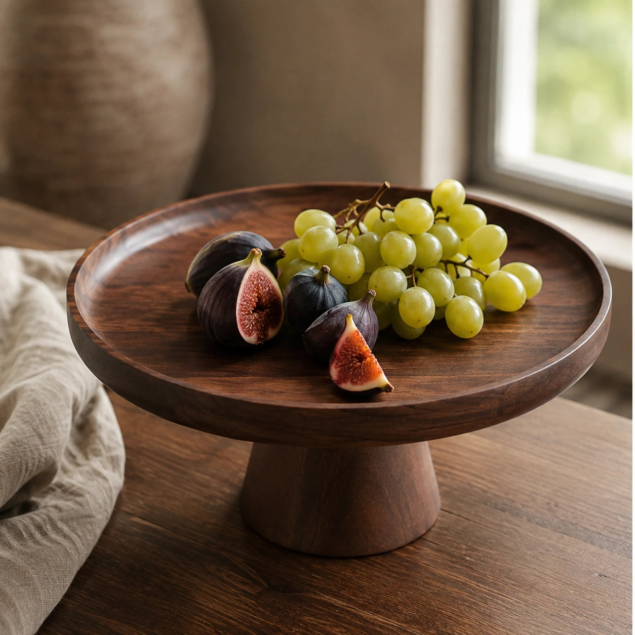 Bandeja pedestal em madeira escura decorada com figos e uvas em ambiente acolhedor