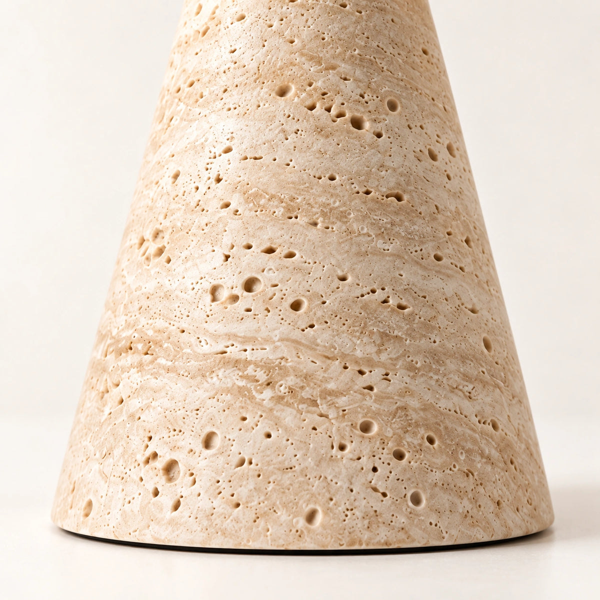Detalhe da base em travertino da Luminária Eloíse com textura natural e poros característicos da pedra