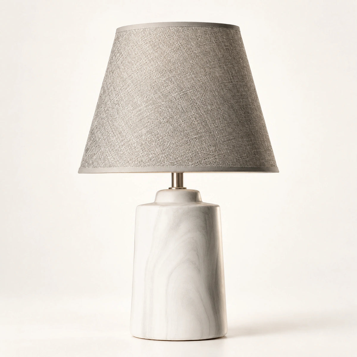 Luminária de mesa mineral com base em cerâmica clara e cúpula greige sobre fundo branco