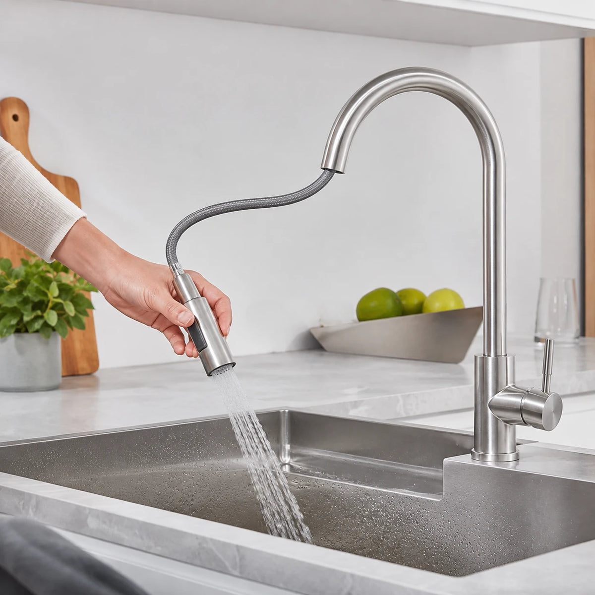 Pessoa utilizando a ducha extensível da Torneira Sienne sobre a cuba da cozinha